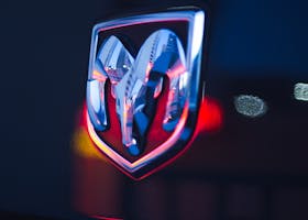 pexels-photo-3767673-3767673 Close-up of a chrome Dodge Ram emblem with neon bokeh lighting in the background at night.